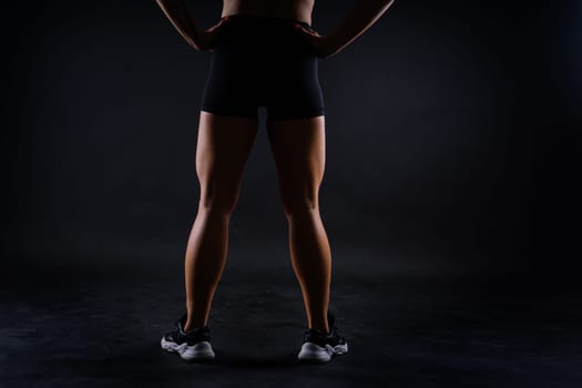 Shaped female legs in sneakers sculpted muscles, dark background