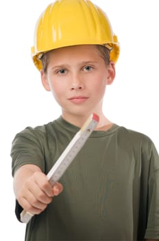 Upper part view of a young teenage boy wearing a yellow hard hat pointing at the camera with his right hand and a folding ruler.