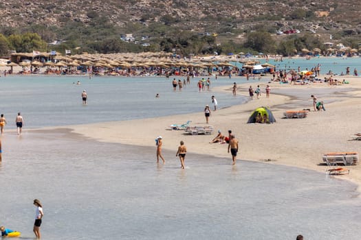 Elafonisi, Crete, Greece - Sept 19, 2021: People relaxing on the famous pink coral beach of Elafonisi on Crete, Mediterannean sea, Greece
