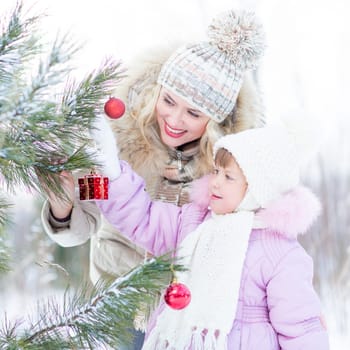 Happy mother and child decorating christmas tree outdoor