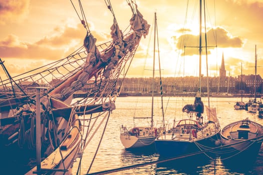 Old corsair ship and boats in the port of historical city Saint Malo at sunset, also known as city corsaire, Brittany, France. Real photoraphy