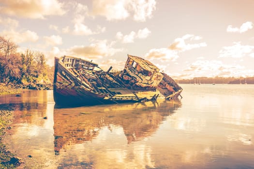 Wreck of a wooden fishing boat abandonedon the shore, Quelmer near Saint-Malo, France. Real photography