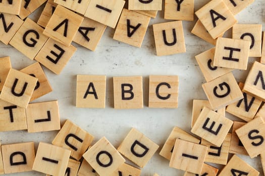 Top down view, pile of square wooden blocks with letters ABC on white board.