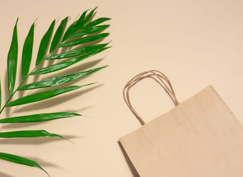Empty disposable brown kraft paper bag with handles on beige background, eco packaging, zero waste