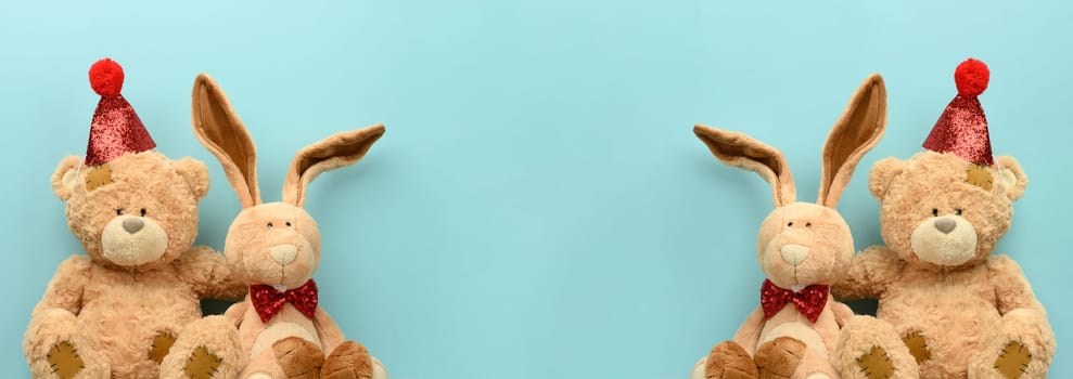 Teddy bear in a festive cap and a plush hare on a blue background. Festive background
