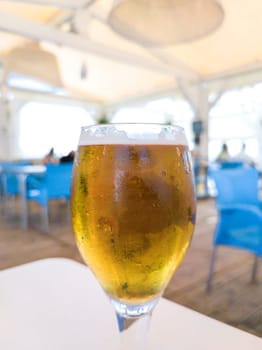Glass chalice of beer over beach terrace. Spanish chiringuito background