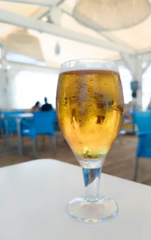 Glass chalice of beer over beach terrace. Spanish chiringuito background