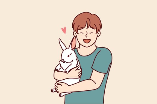 Boy with little rabbit laugh hugging beloved pet for concept of love for domestic animals. Happy child with white eared rabbit for advertising pet store with goods for pets and their owners