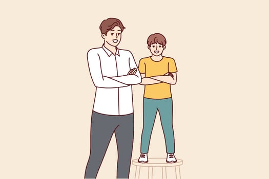 Father and son smiling standing with arms crossed and looking at screen for concept of intergenerational succession and parenthood. Little boy stands on stool near father or older brother