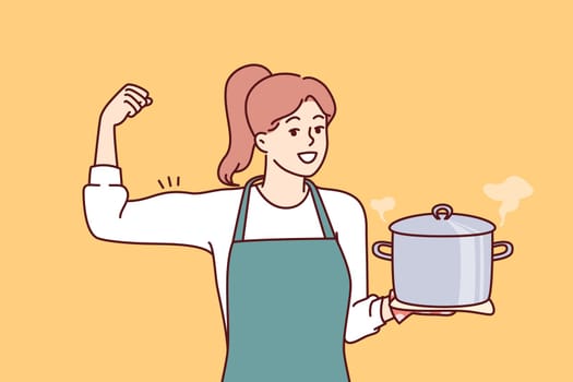 Woman cook holds pot of soup and shows biceps as sign of pride in ability to cook complex dish. Girl housewife in apron smiles inviting to eat delicious homemade food from healthy ingredients