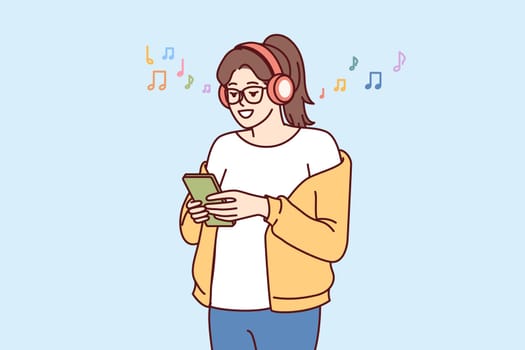 Teen girl listens music on headphones and holds phone with application