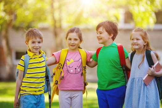 Group of children standing with backpacks near the school. Concept of the back to school and friendship.