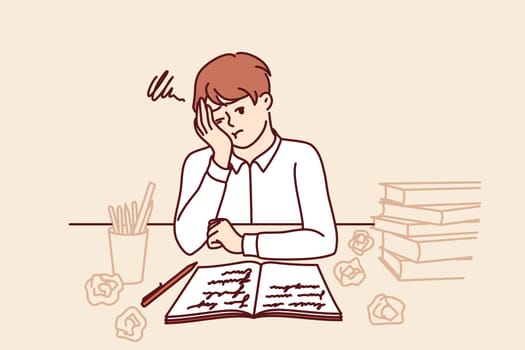 Thinking schoolboy does homework sitting at table with books and workbook after exhausting classes with tutor. Tired schoolboy from elementary school needs rest to replenish strength