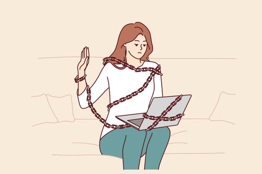 Addicted woman with laptop sits on couch chained for internet dependent concept. Addicted freelance girl working from home suffers from work overload and strict deadlines causing problems