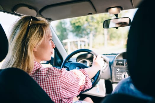 Young blond woman driving car. Hipster girl driver travel in vehicle.