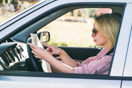Happy couple traveling by car in nature and looking in map. Carefree friend travelers on countryside roadtrip journey. Young woman and man driving to adventure holiday.