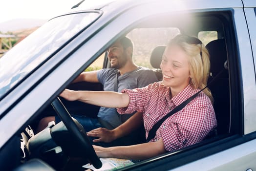 Happy couple traveling by car in nature. Carefree friend travelers on countryside roadtrip journey. Young woman and man driving on romantic weekend.