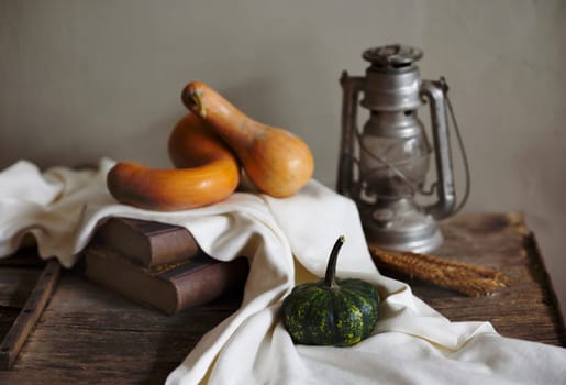 Autumn still life with vintage lantern and pumpkin vegetable on rustic wooden table. Thanksgiving and halloween holiday design concept.