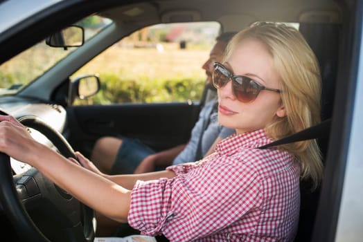 Happy couple traveling by car in nature. Carefree friend travelers on countryside roadtrip journey. Young woman and man driving on romantic weekend.