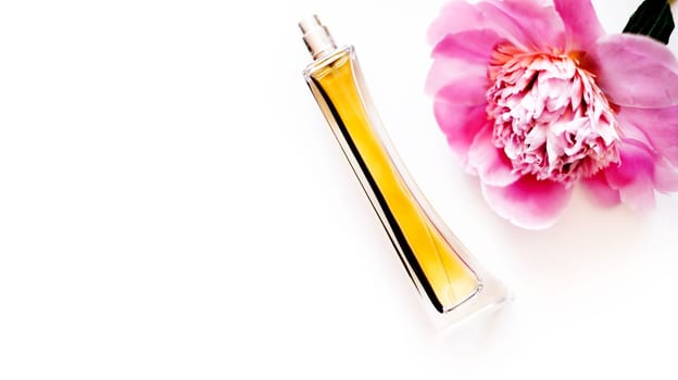Top view of luxury perfume bottle and pink peony flower isolated on white background. Female cosmetic and makeup accessory still life. Feminine cologne spray overhead.
