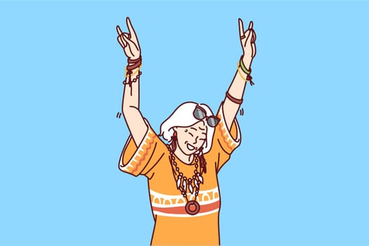 Mature hippie woman in fashionable clothes and accessories enjoys life dancing at parties. Elderly woman with gray hair having fun after retirement visiting carnivals or festivals for hippie