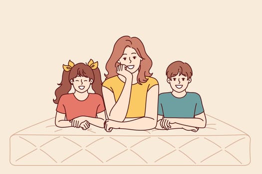 Mother and children lie on mattress recommending use of high-quality and comfortable furniture for bedroom and sleep. Happy woman together with kids with mattress for healthy rest after hard day