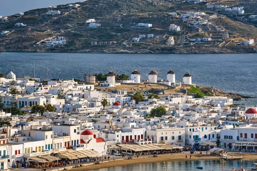 Beautiful close view, Chora, main town of Mykonos, Cyclades, Greece, and its famous landmark: white windmills Whitewashed houses with colorful windows and roofs and distant islands in background. Vacations, leisure, Mediterranean lifestyle