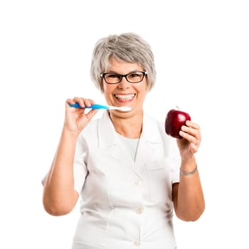 Elderly woman brushing her teeth and holding a red apple