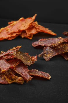 Different kinds of dehydrated jerky meat on black background