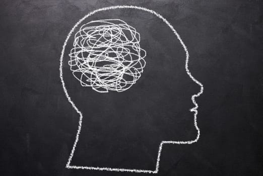 Drawn silhouette of a human head with a tangled ball of yarn in the brain. Concept of confusion, tangled thoughts, search for truth