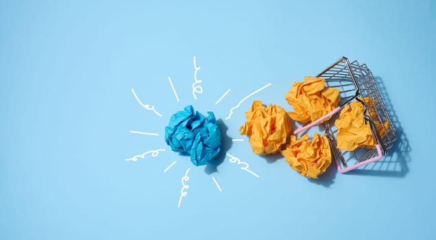 Crumpled paper balls on a blue background and a shopping basket. Concept of a new idea
