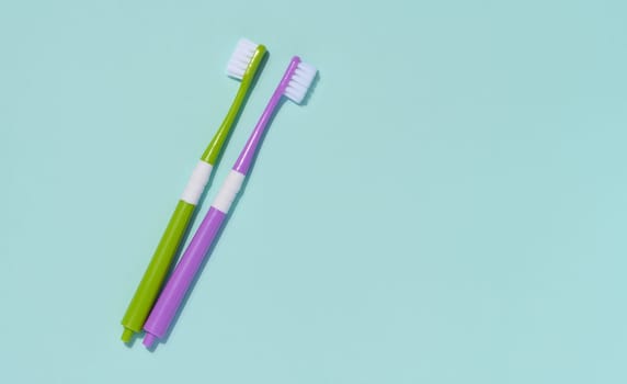 Two plastic toothbrushes on a blue background, oral hygiene.