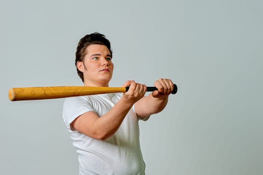 A man with a bat in his hands swings on a gray background. High quality photo