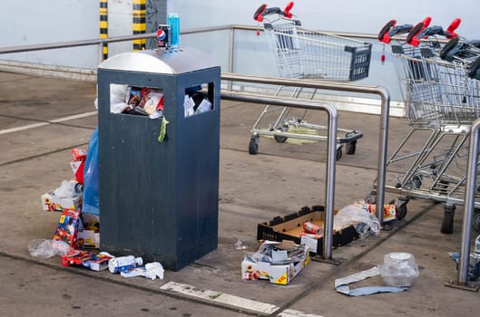 Overflowing dumpster, trash can with plastic bags and cardboard, filthy shopping center, Alleencenter in Trier, Germany