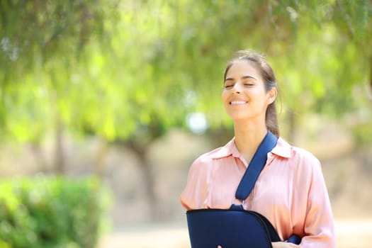 Happy convalescent woman breathing fresh air in a green park