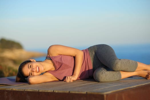 Happy yogi resting in a wooden platform laughing on the beach
