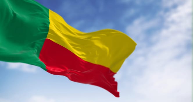 National flag of Benin waving on a clear day. Two horizontal yellow and red bands on the fly side and a green vertical band at the hoist. 3d illustration render. Fluttering fabric. Selective focus