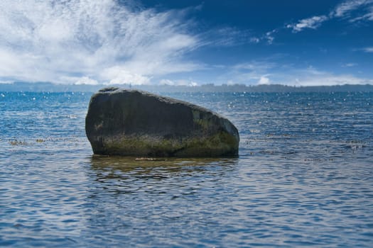 Single stone, rock in the Baltic Sea in sunshine. Landscape photo from the coast.