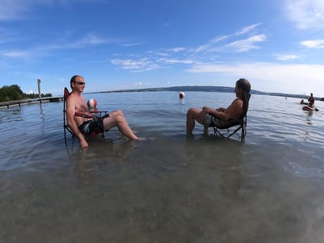 Theme picture Summer - Summer day at Lake Constance  This is how it can be endured: Despite the summer heat,these two men have positioned their sitting chair right in Lake Constance and thus find the right cooling not only for their feet.  Young and old sought to cool off on a boat trip,an excursion with the Stand Up Paddle (SUP) or while swimming. The next few days are expected to remain hot in summer if thunderstorms are likely to occur