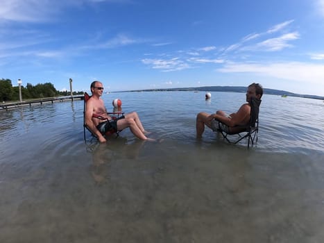 Theme picture Summer - Summer day at Lake Constance  This is how it can be endured: Despite the summer heat,these two men have positioned their sitting chair right in Lake Constance and thus find the right cooling not only for their feet.  Young and old sought to cool off on a boat trip,an excursion with the Stand Up Paddle (SUP) or while swimming. The next few days are expected to remain hot in summer if thunderstorms are likely to occur