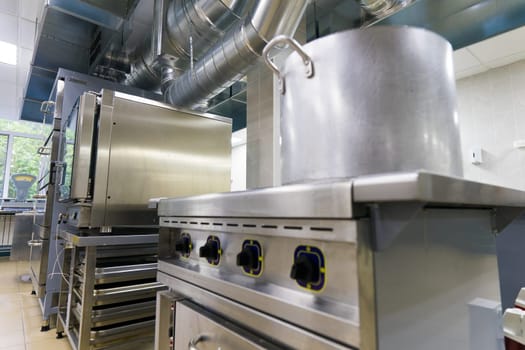Industrial kitchen in school restaurant with professional equipment and pans