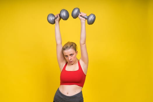 Seductive beautiful fitness female, athletic woman working out with dumbbells. Isolated in a studio