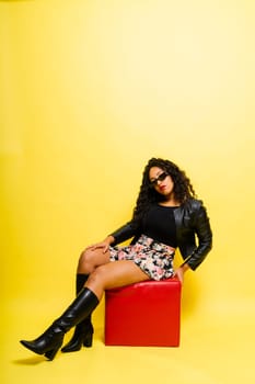 Seductive african woman posing in a black bodysuit and jacket in studio. Fit sporty female.