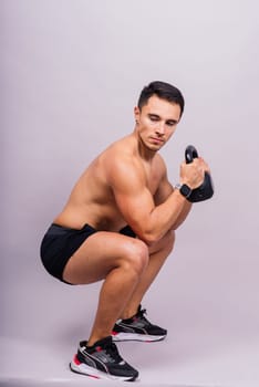 Handsome muscular man holding a kettle bell with copy space. Hispanic male athlete