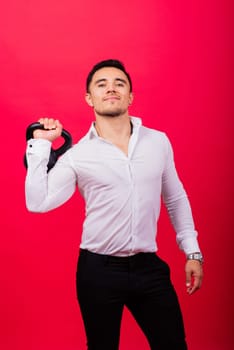 Attractive businessman Exercising With Kettlebell In a studio, red background