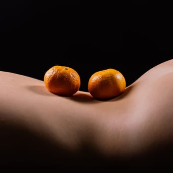 Oranges, tangerines - citrus on woman's body. Naked woman lying on her back with fruit located