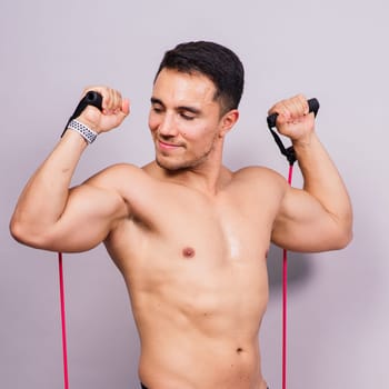 Fit young athlete preparing for a bicep muscle arms exercise. Isolated over grey studio background.