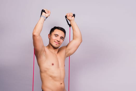 Fit young athlete preparing for a bicep muscle arms exercise. Isolated over grey studio background.