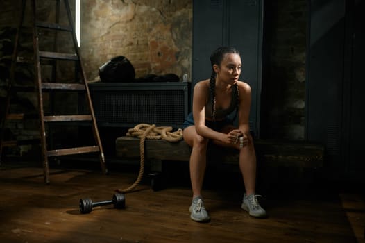 Pensive woman boxer on break from exercise and training. Sport, fitness young girl resting after physical match looking exhausted during routine workout