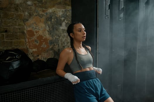Athletic young woman boxer feeling tired and energy loss after hard boxing or kickboxing workout training at gym class. Martial arts for female